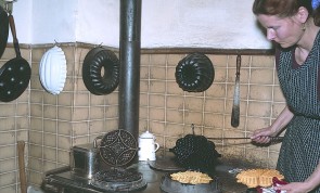 Die Hauswirtschafterin des Museums backt auf der 'Kochmaschine'  Waffeln im gußeisernen Waffeleisen