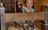 Ein Junge hilft dem Seiler bei der Herstellung eines Seiles. Er dreht die Handkurbel