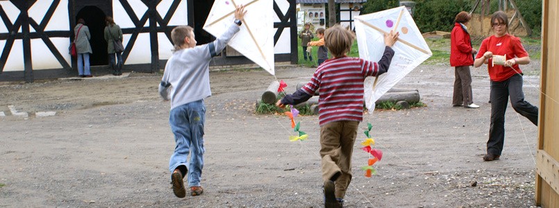 Kinder laufen mit selbstgebastelten Papierdrachen über den Hof von Oberlingenbach
